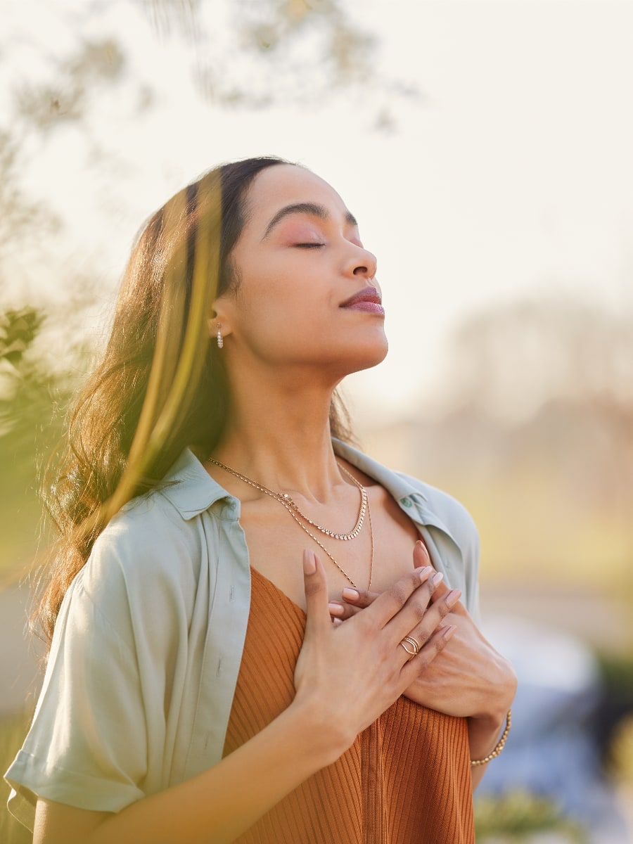 woman looking up serenely into the air while holding her hands over her heart