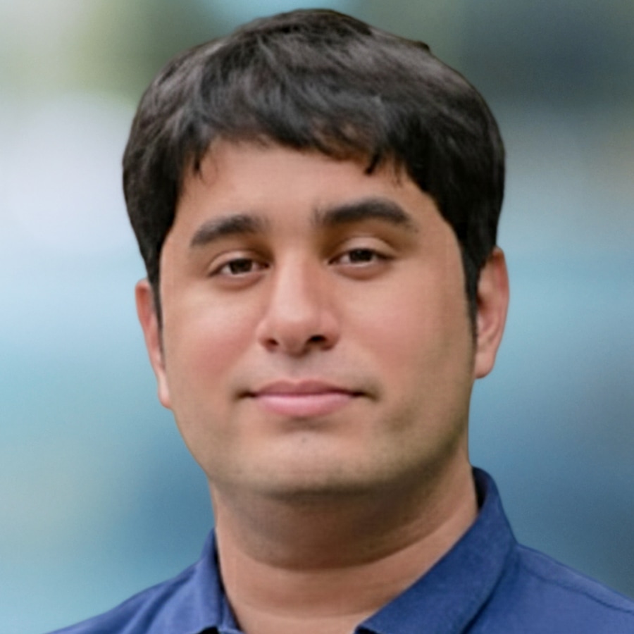 Sohaib Javed, a therapist, wears a blue collared shirt and looks directly at the camera with a friendly, composed expression against a blurred blue and green background.